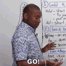 a man stands in front of a white board with the words go on the bottom