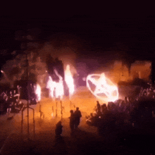 a group of people are gathered in a dark room with a car on fire