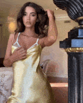 a woman in a yellow dress is standing in front of a black column