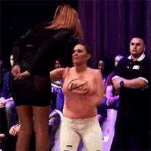 a woman is dancing in front of a crowd while a man watches .