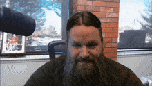 a man with a beard is sitting in front of a brick wall with a picture of a man on it