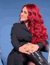 a woman with long red hair is sitting in a chair
