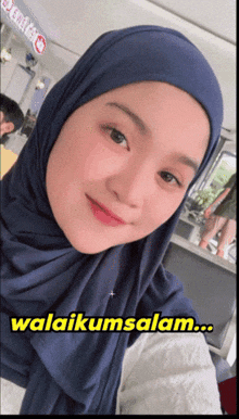 a woman wearing a blue hijab with the words ' awalikumsalam ' on the bottom