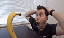 a man wearing a black shirt that says converse is looking at a banana