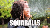 a woman with dreadlocks and glasses says squarballs in front of trees