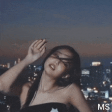 a woman is standing in front of a city skyline with the letters ms on the bottom right