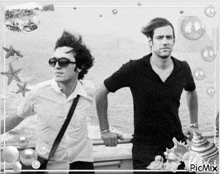 two men are standing next to each other in a black and white photo with bubbles and seashells in the background