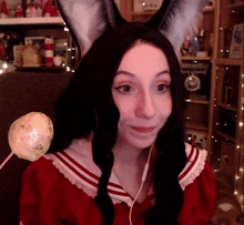 a woman wearing bunny ears and a red dress holds a marshmallow on a stick