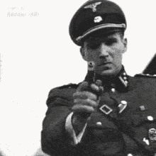 a black and white photo of a man in a military uniform holding a gun .