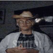 a man wearing a cowboy hat and glasses is sitting in front of a sign that says start