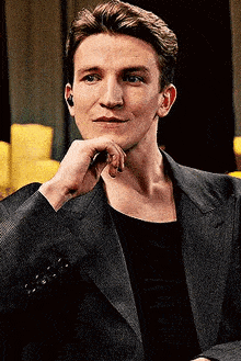a man in a suit and ear buds is looking at the camera .