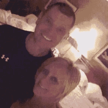 a man and woman are posing for a picture and the man is wearing a black under armour shirt