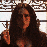 a woman with blood on her face holds a cigarette in her hand
