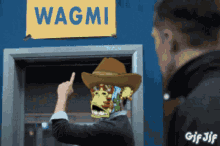 a man wearing a cowboy hat is pointing at a sign that says wagmi