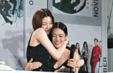 a woman hugging another woman in front of a sign that says november