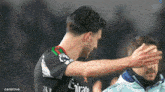 a soccer player wearing an emirates jersey is hugging another player .