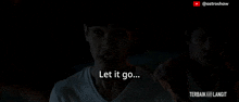 a man in a white shirt says let it go in a dark room