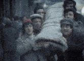 a group of men are carrying a large bag on their backs