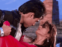 a man and a woman are kissing in front of a building