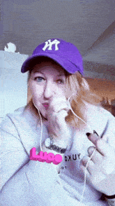 a woman wearing a purple ny hat and a luce sweatshirt