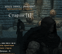 a man in a hood stands in front of a brick wall with a target in the background that says starik 1