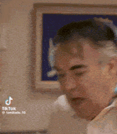 a man is making a funny face in front of a picture on the wall .