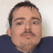 a man with a beard is making a funny face with his eyes closed .