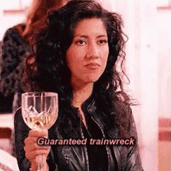 a woman in a leather jacket is holding a wine glass with the words `` guaranteed trainwreck '' written on it .