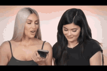 kim kardashian and kylie jenner are looking at a cell phone together