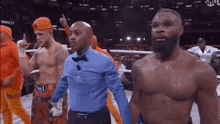 three men are standing in a boxing ring with a referee .