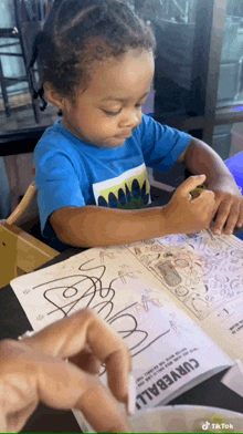 a little boy in a blue shirt is sitting at a table with a book open to a page that says curverall