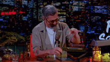 a man with a tattoo on his arm is sitting at a desk with a microphone and a sign that says la