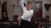 a man in a tuxedo is swinging a sword in a room