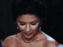 a woman wearing a necklace and earrings smiles