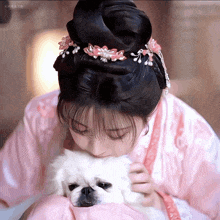 a woman in a pink dress is holding a small dog