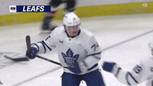 a hockey player in a leafs jersey holds a puck