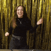 a woman in a black shirt is dancing in front of a gold curtain with ritualas written on the bottom