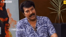 a man with a mustache wearing a blue and white paisley shirt