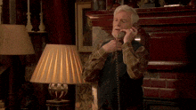 an older man talking on a telephone with the words well at least behind him