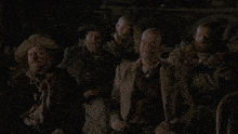 a group of men wearing suits and cowboy hats are sitting in a dark room