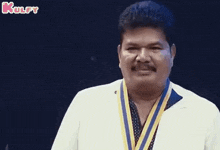a man wearing a medal around his neck is smiling and looking at the camera .