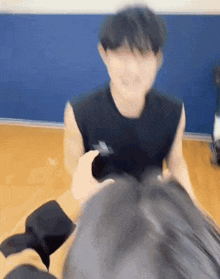 a man in a black tank top is sitting on a wooden floor with another man .