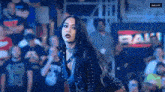 a woman in a black leather outfit is standing in front of a crowd in a stadium .