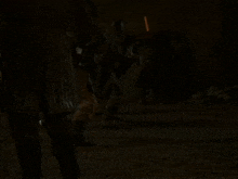 a man in armor is holding a sword in his hand in a dark room .