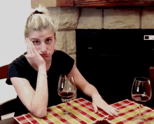 a woman is sitting at a table with a glass of wine