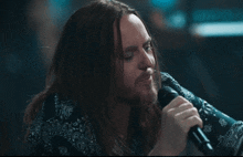a man with long hair singing into a microphone