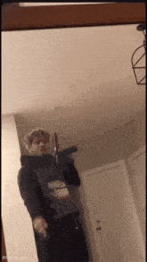 a young man is standing in front of a mirror holding a gun .