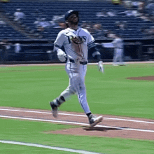 a baseball player wearing a rays jersey is running on the field
