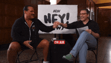two men shake hands in front of an aew sign