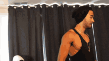 a shirtless man wearing a black beanie and a tank top